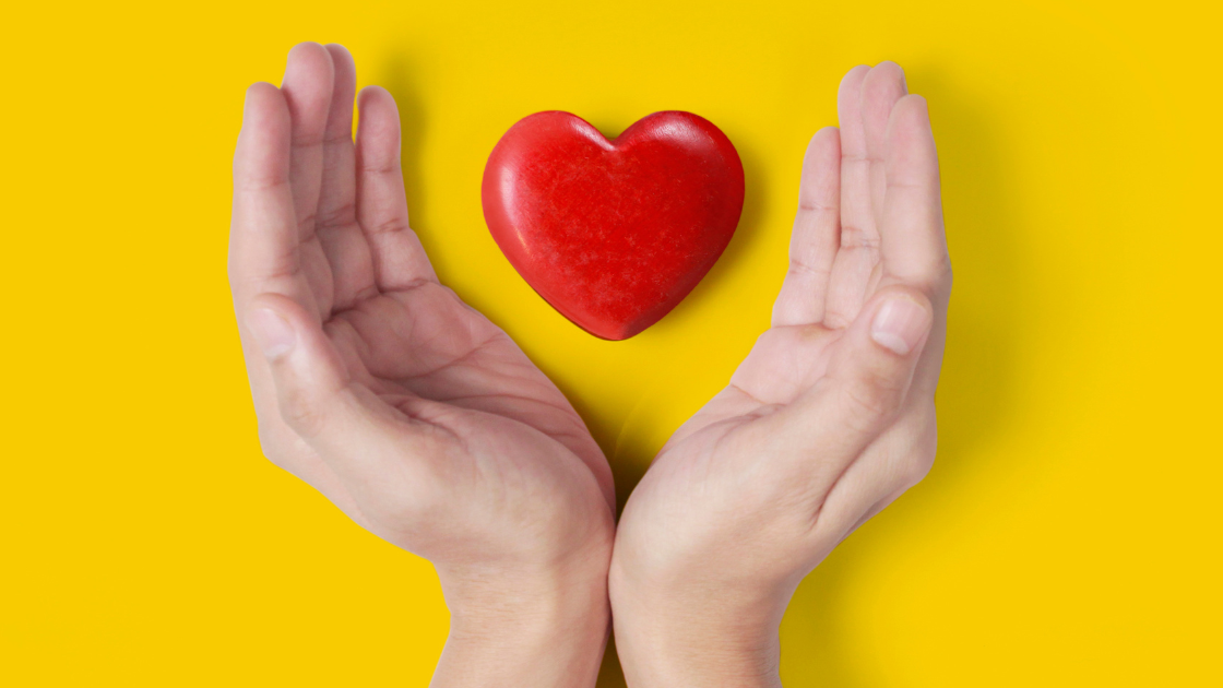 Red heart floating, with two hands on both sides, yellow background.